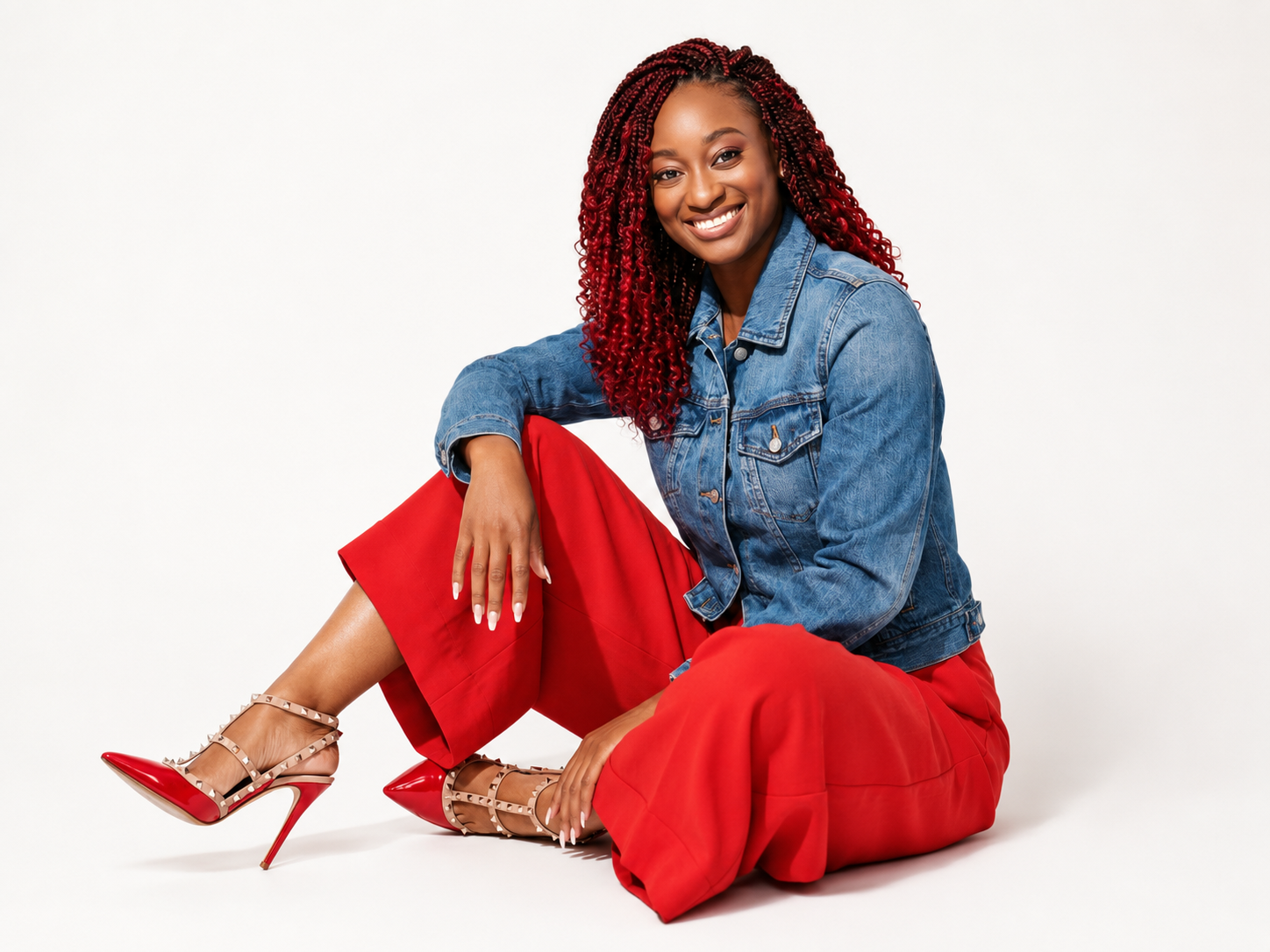Shiloh Moyo seated in a denim jacket and red trousers