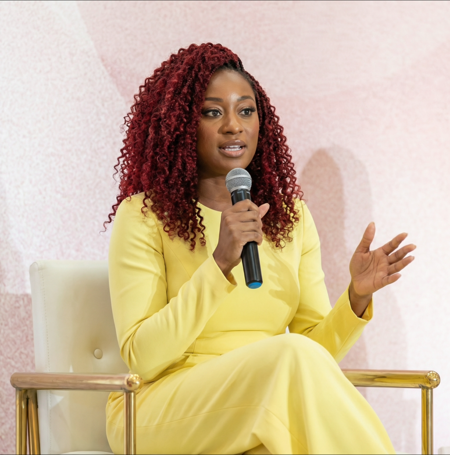 Shiloh Moyo speaking on a panel in a yellow dress